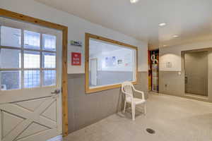 Doorway with a wainscoted wall, tile patterned floors, tile walls, and recessed lighting