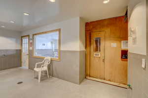 Hallway with recessed lighting, wainscoting, and tile walls