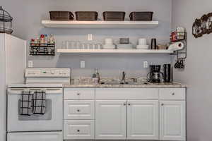 Bar featuring white range with electric stovetop, a sink, and refrigerator