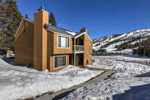 Snow covered property with metal roof, stairway, a chimney, and a mountain view