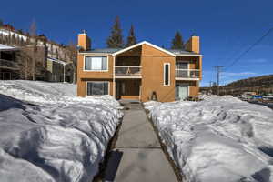 Chalet / cabin featuring a balcony, a chimney, metal roof, and stucco siding