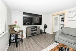 Living area with light wood-type flooring, baseboards, and stacked washer / dryer