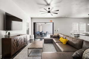 Living area featuring baseboards, visible vents, a ceiling fan, wood finished floors, and a textured ceiling