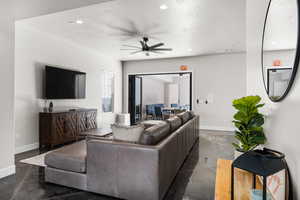 Living room featuring a textured ceiling, baseboards, concrete flooring, and recessed lighting