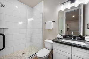 Bathroom featuring toilet, tiled shower, and vanity