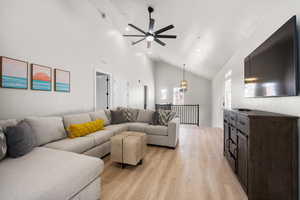 Living room featuring light wood-type flooring, high vaulted ceiling, visible vents, and a ceiling fan