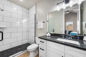 Bathroom with a baseboard radiator, wood finished floors, vanity, a shower stall, and ensuite bath