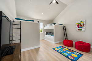 Bedroom featuring a ceiling fan, light wood-type flooring, vaulted ceiling, and baseboards