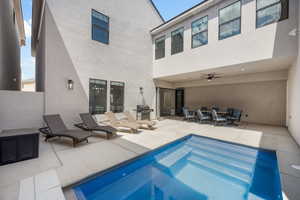 Back of property featuring a ceiling fan, a patio area, an outdoor pool, and stucco siding