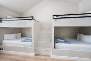 Bedroom with vaulted ceiling, wood finished floors, and visible vents