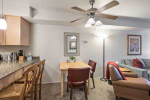 Dining space with a ceiling fan, light colored carpet, and baseboards