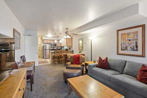 Living area featuring light carpet and ceiling fan