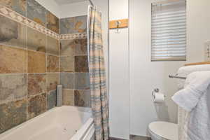 Full bathroom with toilet and shower / bathtub combination with curtain