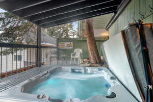 View of swimming pool featuring a covered hot tub and fence