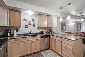 Kitchen with appliances with stainless steel finishes, light brown cabinets, a sink, and a peninsula