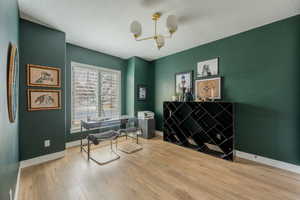 Office with an inviting chandelier, a textured ceiling, baseboards, and wood finished floors