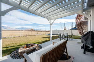 View of patio / terrace featuring an outdoor fire pit, a fenced backyard, outdoor dining area, a mountain view, and a pergola