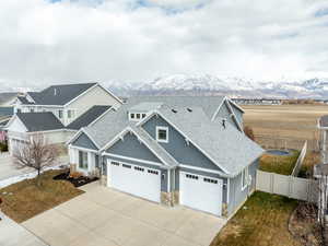 View of front of home with driveway, stone siding, a trampoline, fence, and a mountain view