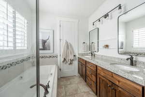 Bathroom featuring a garden tub, a sink, a shower stall, and tile patterned floors