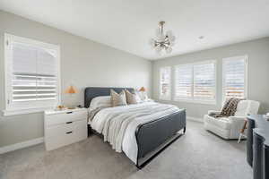 Bedroom with light carpet, an inviting chandelier, and baseboards