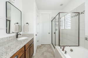 Full bathroom with a stall shower, a garden tub, vanity, and tile patterned floors