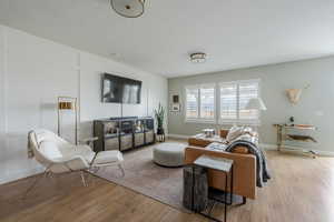 Living area featuring light wood-type flooring, baseboards, and a textured ceiling