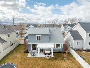 Rear view of property featuring a shingled roof, a residential view, an outdoor living space with a fire pit, and a fenced backyard