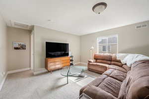 Living room with attic access, visible vents, baseboards, light colored carpet, and a textured ceiling