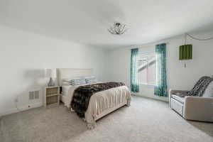 Bedroom with baseboards, a textured ceiling, visible vents, and light colored carpet