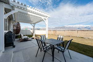 View of patio featuring area for grilling, a fenced backyard, outdoor dining area, a mountain view, and a pergola