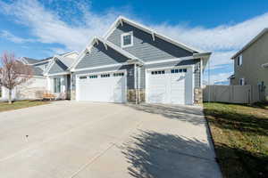 View of front of home featuring stone siding, a gate, driveway, and an attached garage