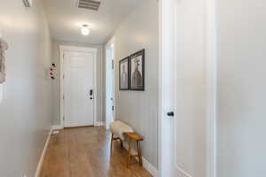 Doorway featuring light wood-style flooring, visible vents, and baseboards