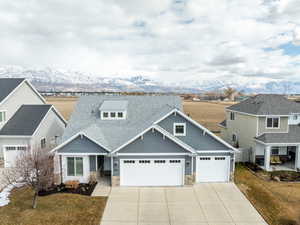 Craftsman-style house featuring a front yard, a mountain view, a garage, stone siding, and driveway