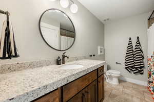 Bathroom with visible vents, toilet, vanity, tile patterned flooring, and baseboards