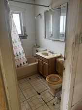 Full bath with plenty of natural light, tile walls, shower / tub combo with curtain, and vanity