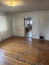 Empty room featuring visible vents, a textured ceiling, and wood finished floors