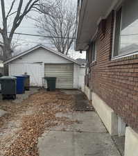 View of side of property featuring an outbuilding, brick siding, and a detached garage