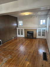 Unfurnished living room featuring a textured ceiling, wood finished floors, a tile fireplace, and visible vents