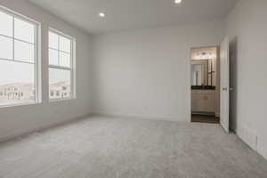 Unfurnished bedroom featuring recessed lighting, visible vents, connected bathroom, and light colored carpet