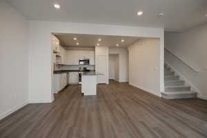 Kitchen featuring a sink, white cabinets, open floor plan, appliances with stainless steel finishes, and dark countertops