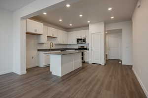 Kitchen with appliances with stainless steel finishes, dark countertops, white cabinets, and a kitchen island