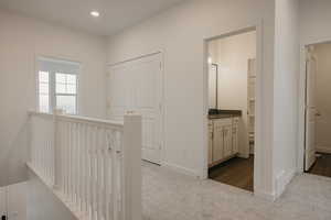 Corridor featuring an upstairs landing, recessed lighting, baseboards, and light colored carpet