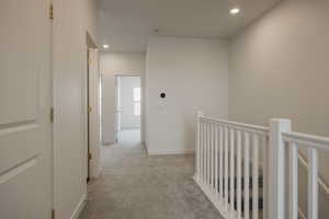 Hallway featuring baseboards, recessed lighting, an upstairs landing, and light colored carpet