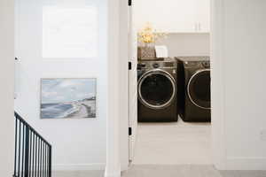 Laundry room featuring baseboards, independent washer and dryer, cabinet space, and light colored carpet