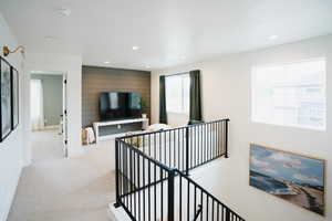 Hallway featuring recessed lighting, baseboards, light carpet, and an upstairs landing