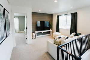 Living room with recessed lighting, light colored carpet, wooden walls, and baseboards