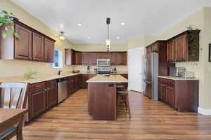 Kitchen with a sink, dark brown cabinets, appliances with stainless steel finishes, a center island, and pendant lighting