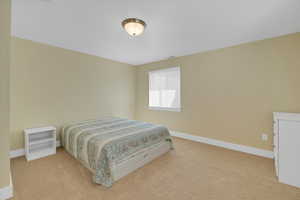 Bedroom featuring light colored carpet, visible vents, and baseboards