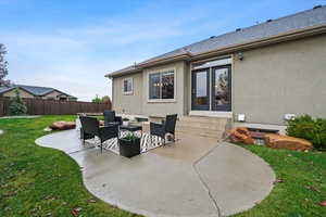 Rear view of house with entry steps, stucco siding, a patio, and fence