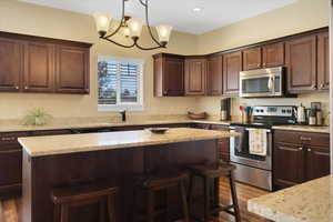 Kitchen with dark brown cabinetry, appliances with stainless steel finishes, a sink, and a center island